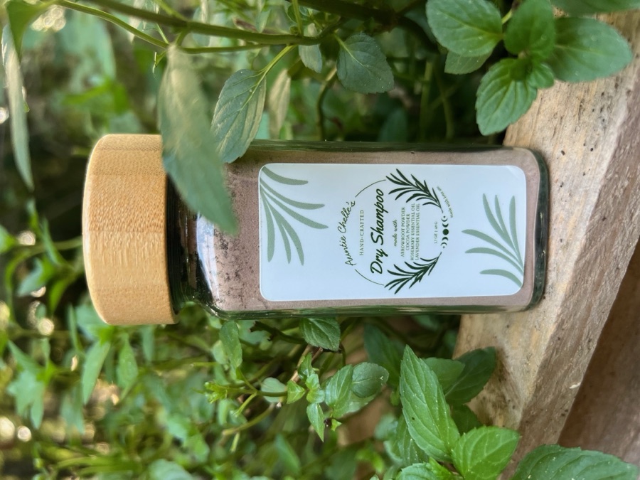 The Dry Shampoo jar on a wooden ledge surrounded by mint